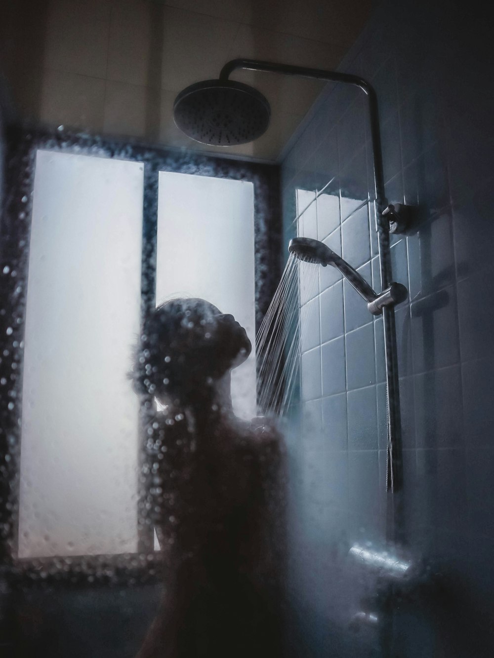 Photo: Hannah Xu · Unsplash Slim inline filter fitted on a shower arm against dark tile